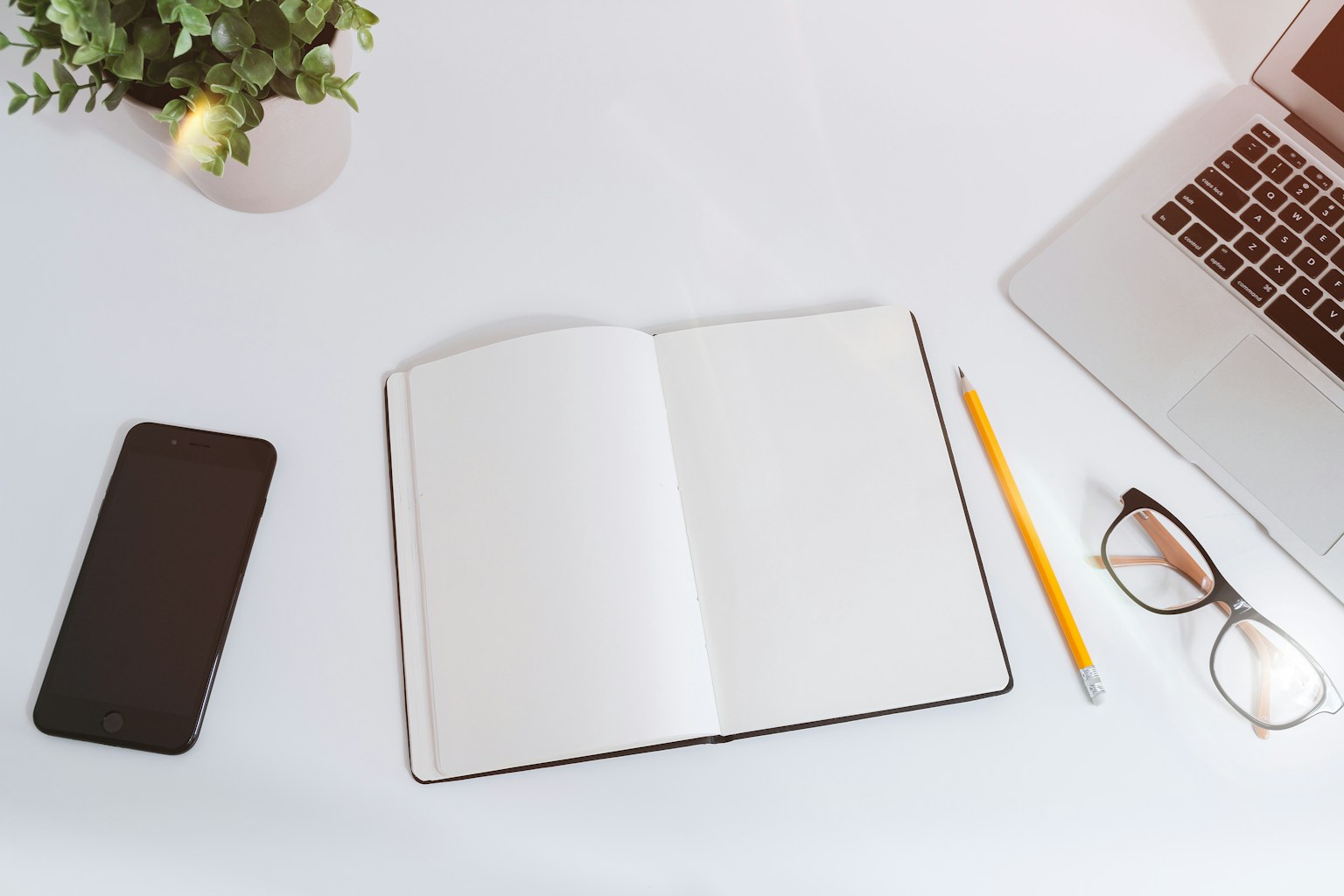 An open notebook beside a smartphone and laptop
